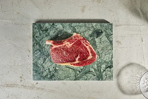 Côte de bœuf crue sur une planche de marbre vert