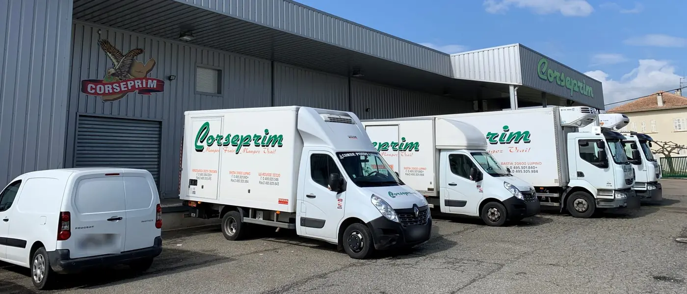 Camions frigorifiques Corseprim garés devant les quais du siège, l'écusson à l'aigle peint sur la façade